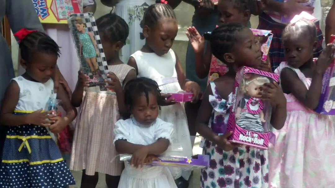 Young Haitian girls wearing dresses and holding dolls